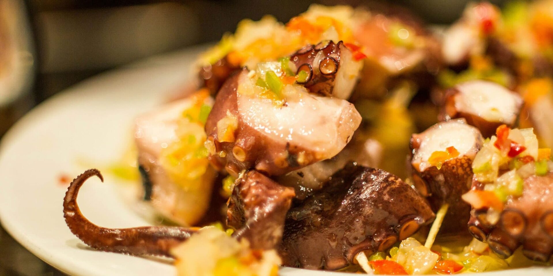 Grilled octopus salad with colorful diced vegetables.