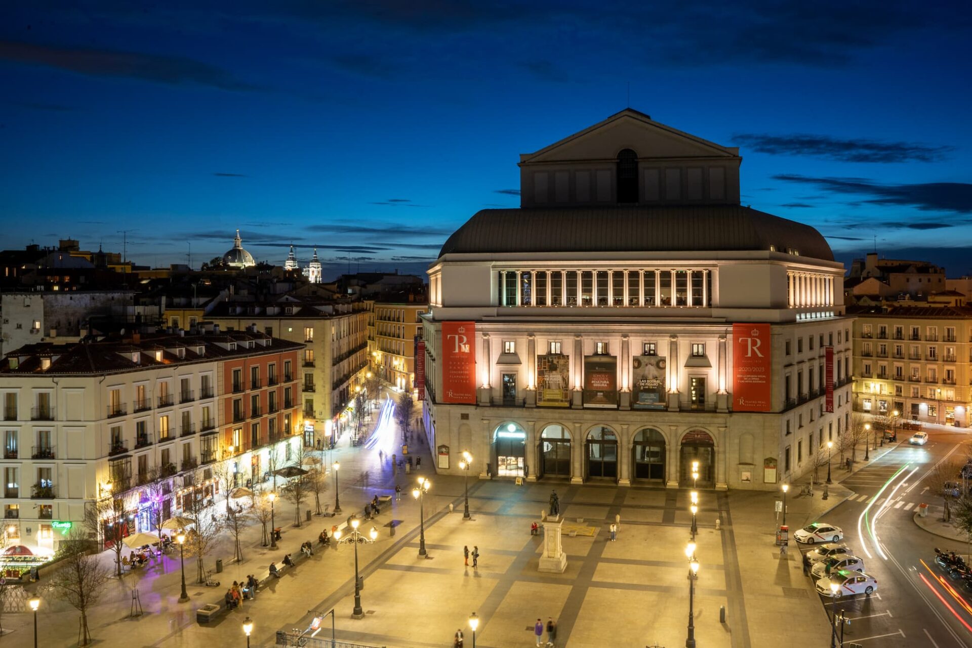 Royal Theater Madrid at twilight with illuminated streets.